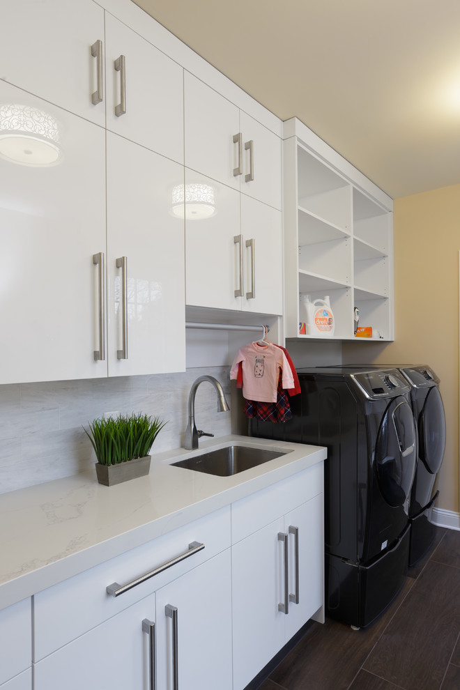 Large modern u-shaped utility room in Philadelphia with a single-bowl sink, flat-panel cabinets, white cabinets, engineered stone countertops, yellow walls, dark hardwood flooring, a side by side washer and dryer, brown floors and white worktops.