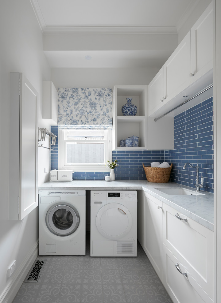 メルボルンにあるお手頃価格の小さなトランジショナルスタイルのおしゃれな家事室 (L型、ドロップインシンク、インセット扉のキャビネット、白いキャビネット、大理石カウンター、青い壁、セラミックタイルの床、洗濯乾燥機、マルチカラーの床、白いキッチンカウンター) の写真