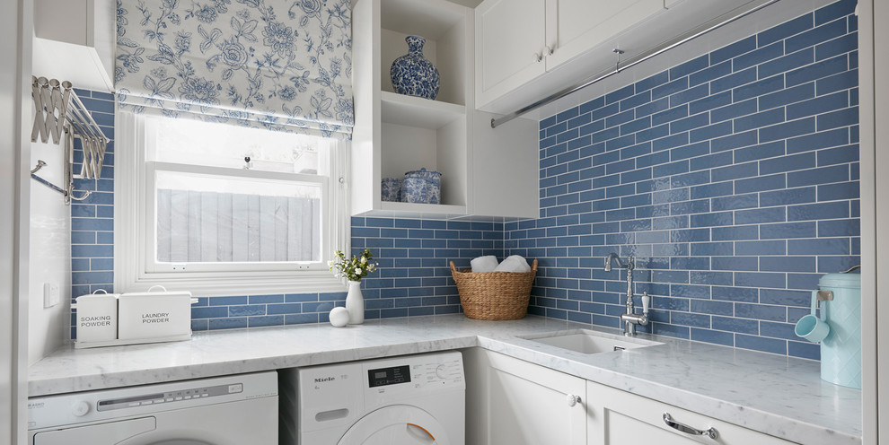 This is an example of a small traditional l-shaped utility room in Melbourne with a built-in sink, beaded cabinets, white cabinets, marble worktops, blue walls, ceramic flooring, an integrated washer and dryer, multi-coloured floors and white worktops.