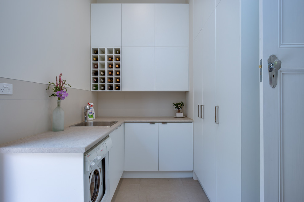 Mittelgroße Moderne Waschküche in L-Form mit weißen Schränken, Mineralwerkstoff-Arbeitsplatte, Porzellan-Bodenfliesen und flächenbündigen Schrankfronten in Melbourne