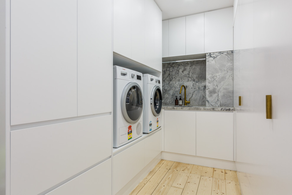 Exempel på en liten modern grå u-formad grått tvättstuga enbart för tvätt och med garderob, med en nedsänkt diskho, vita skåp, marmorbänkskiva, grått stänkskydd, stänkskydd i marmor, vita väggar och ljust trägolv