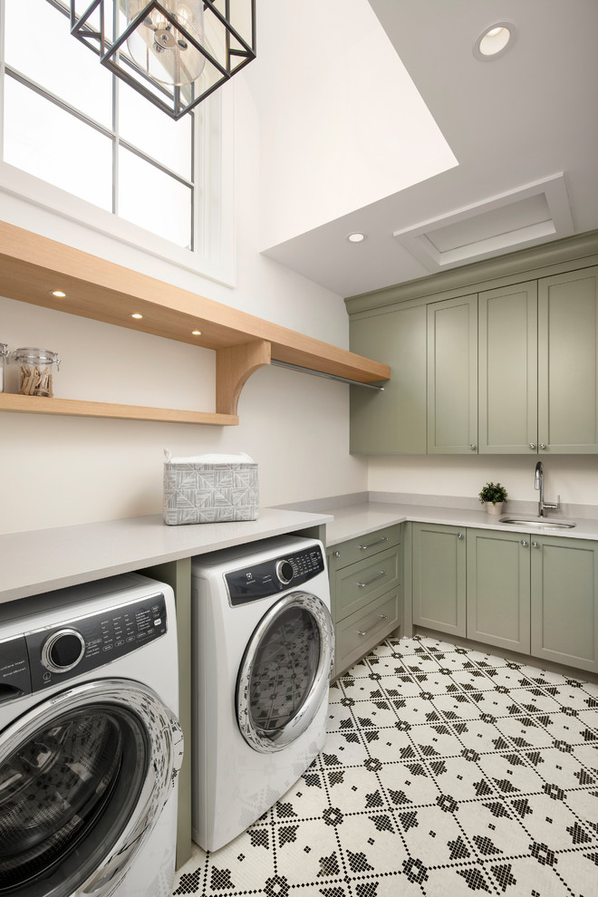 Inspiration för klassiska l-formade grått tvättstugor enbart för tvätt, med en undermonterad diskho, luckor med infälld panel, gröna skåp, bänkskiva i kvarts, vita väggar, marmorgolv, en tvättmaskin och torktumlare bredvid varandra och vitt golv