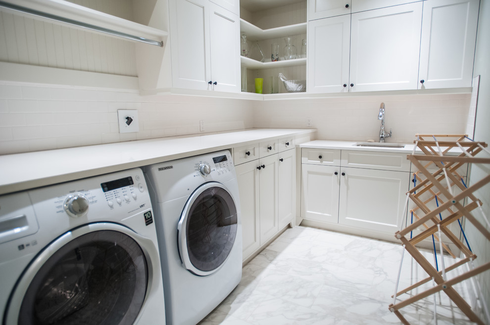 Große Klassische Waschküche in L-Form mit Unterbauwaschbecken, Schrankfronten im Shaker-Stil, weißen Schränken, Quarzwerkstein-Arbeitsplatte, weißer Wandfarbe, Porzellan-Bodenfliesen und Waschmaschine und Trockner nebeneinander in Calgary