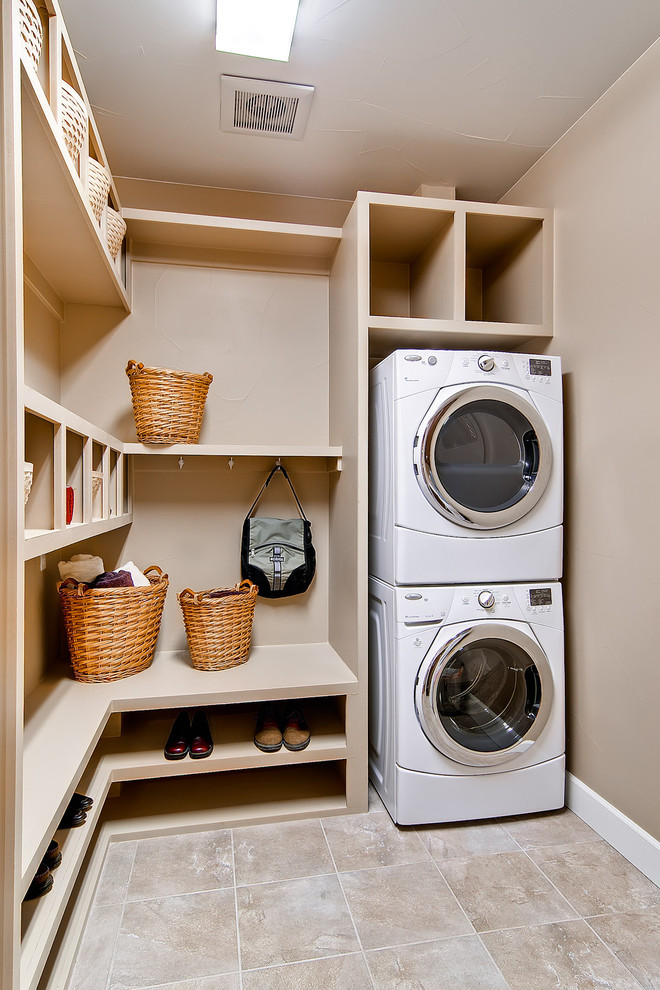Ejemplo de lavadero multiusos clásico de tamaño medio con lavadora y secadora apiladas, paredes beige y suelo beige