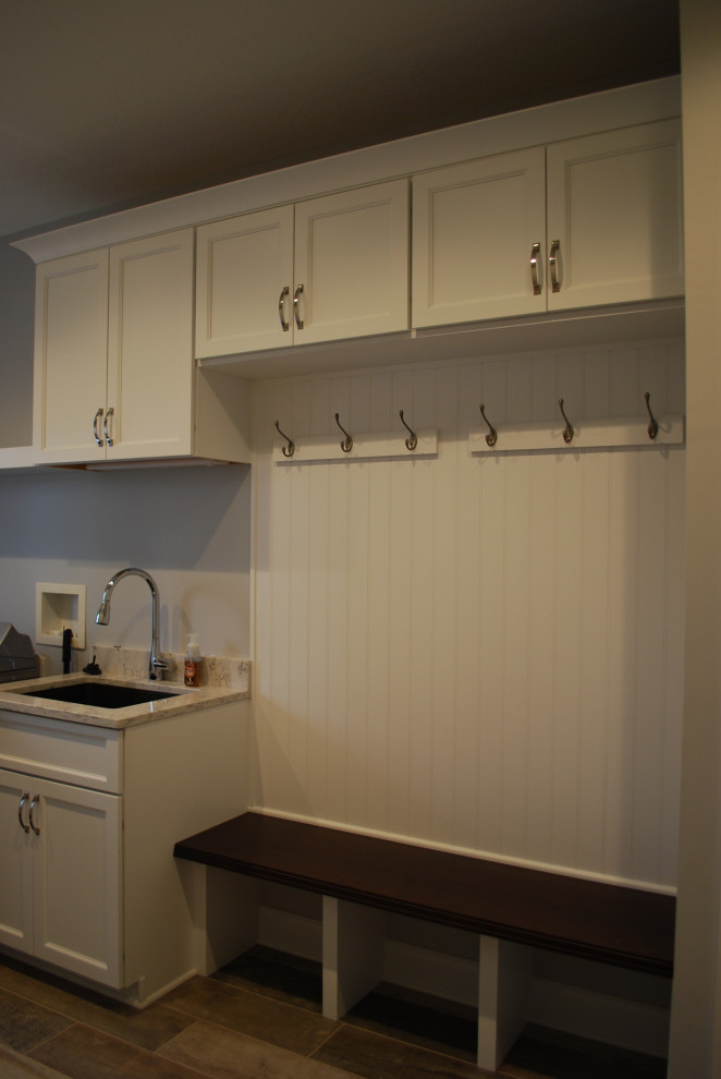 Photo of a large traditional u-shaped utility room in Cleveland with a belfast sink, shaker cabinets, white cabinets, engineered stone countertops, medium hardwood flooring, brown floors and white worktops.