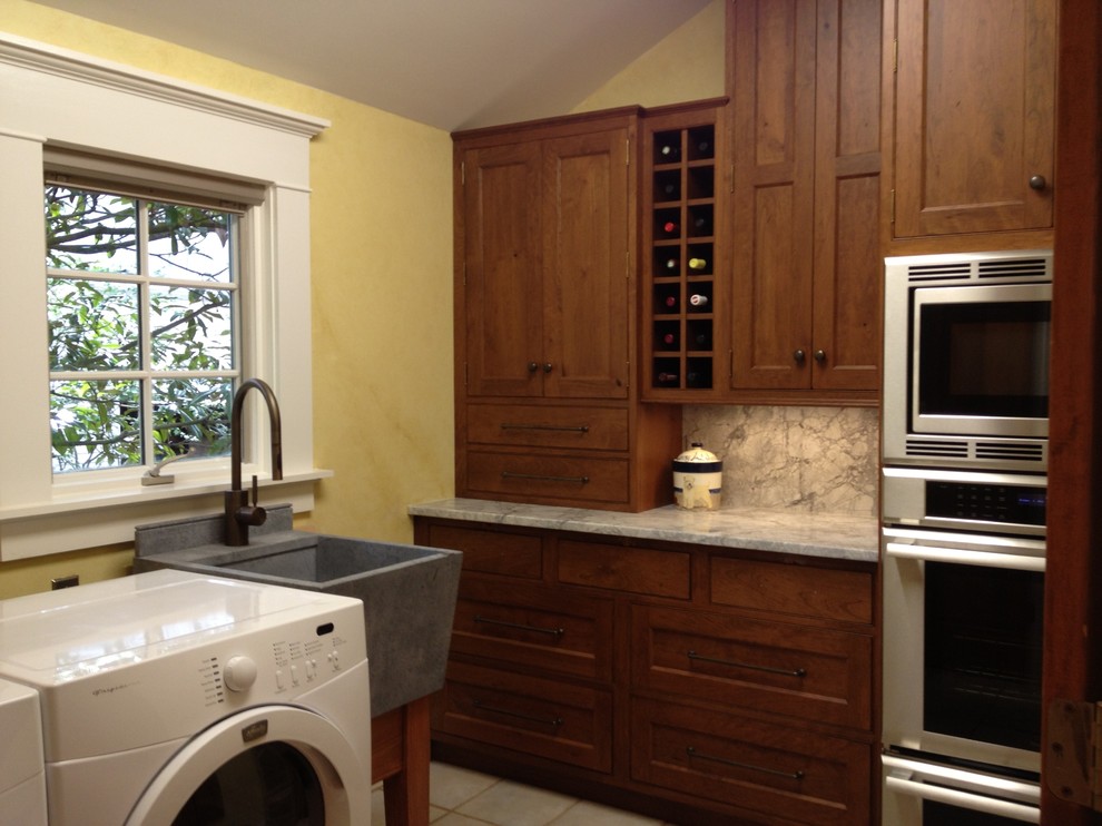 Exempel på ett mellanstort klassiskt l-format grovkök, med en rustik diskho, luckor med infälld panel, skåp i mellenmörkt trä, marmorbänkskiva, gula väggar, klinkergolv i keramik och en tvättmaskin och torktumlare bredvid varandra