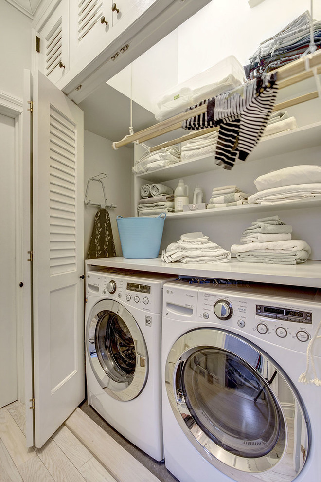 Kleiner Hauswirtschaftsraum mit Waschmaschinenschrank, Quarzwerkstein-Arbeitsplatte, weißer Wandfarbe, Keramikboden und Waschmaschine und Trockner nebeneinander in New York