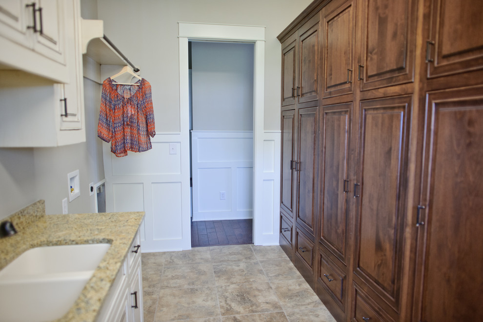 Immagine di una grande sala lavanderia american style con lavello a doppia vasca, ante con bugna sagomata, ante beige, top in granito, pareti beige e pavimento in gres porcellanato