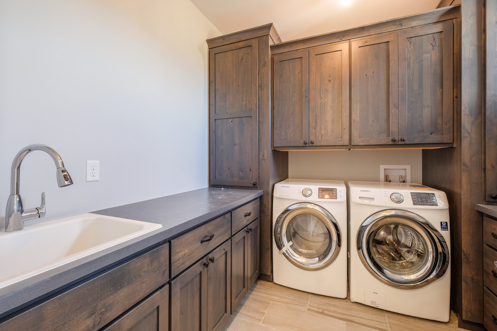Dedicated laundry room - mid-sized cottage u-shaped ceramic tile dedicated laundry room idea in Denver with a drop-in sink, shaker cabinets, dark wood cabinets, solid surface countertops, gray walls and a side-by-side washer/dryer