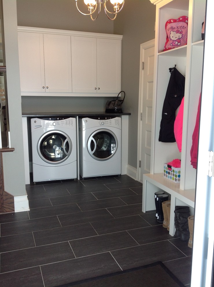 Inspiration for a large traditional l-shaped utility room in Montreal with shaker cabinets, white cabinets, laminate countertops, grey walls, porcelain flooring and a side by side washer and dryer.