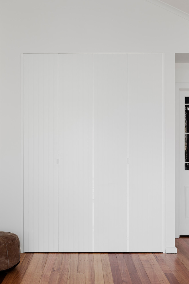 メルボルンにあるお手頃価格の小さなコンテンポラリースタイルのおしゃれな家事室 (ll型、白い壁、無垢フローリング、目隠し付き洗濯機・乾燥機) の写真