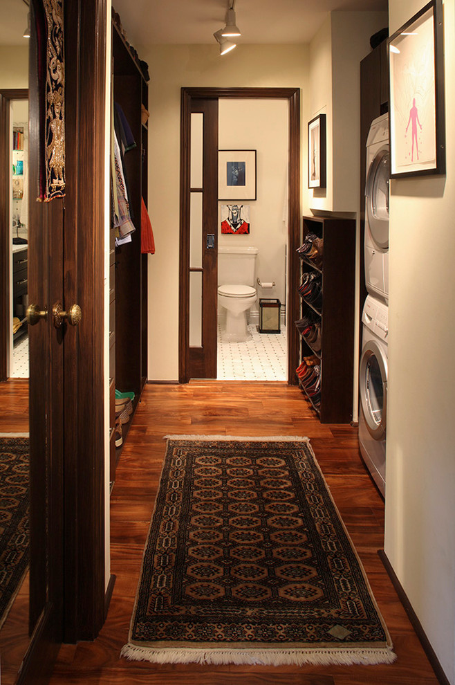 Multifunktionaler, Kleiner Stilmix Hauswirtschaftsraum mit Waschmaschine und Trockner gestapelt, weißer Wandfarbe und braunem Holzboden in San Francisco