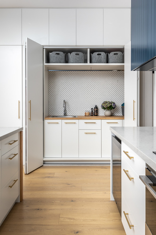 Foto de cocina lineal actual con fregadero encastrado, armarios con paneles lisos, puertas de armario blancas, encimera de laminado y suelo de madera clara