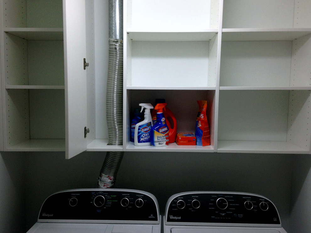 Immagine di una piccola sala lavanderia tradizionale con ante lisce, ante bianche, pareti bianche, pavimento in linoleum e lavatrice e asciugatrice affiancate