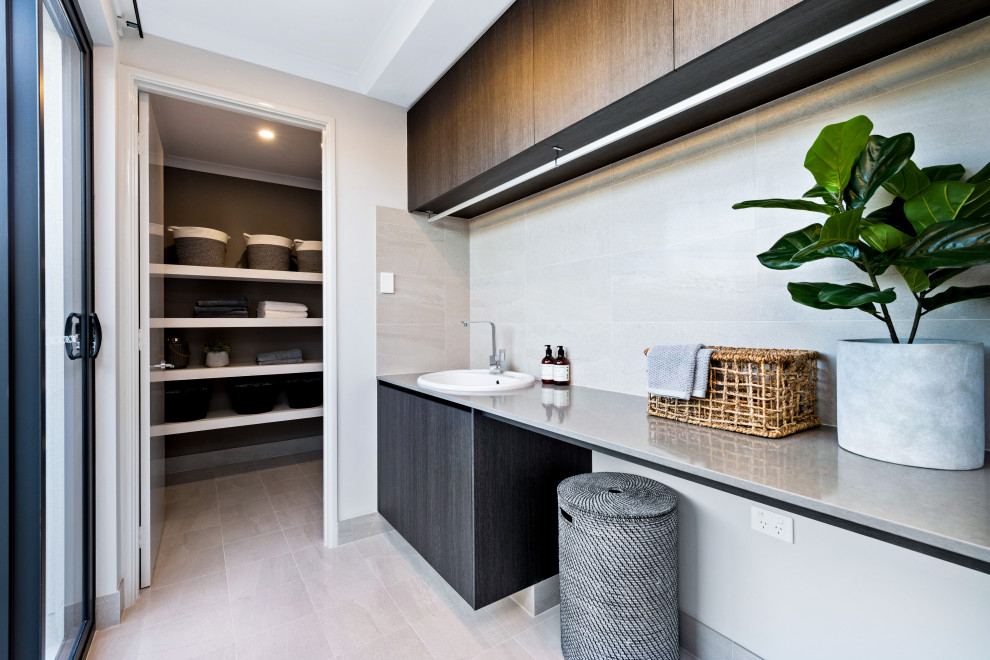 This is an example of a large contemporary single-wall utility room in Perth with a built-in sink, flat-panel cabinets, grey cabinets, white walls, beige floors and grey worktops.
