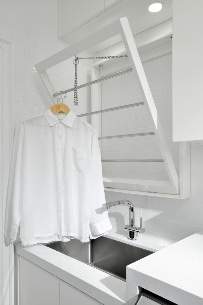 Foto de lavadero lineal tradicional renovado con puertas de armario blancas, encimera de cuarzo compacto, paredes blancas y lavadora y secadora juntas