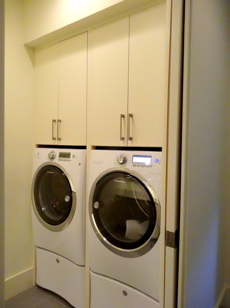 Dedicated laundry room - mid-sized contemporary single-wall ceramic tile dedicated laundry room idea in Charlotte with an undermount sink, flat-panel cabinets, beige cabinets, granite countertops, beige walls and a side-by-side washer/dryer