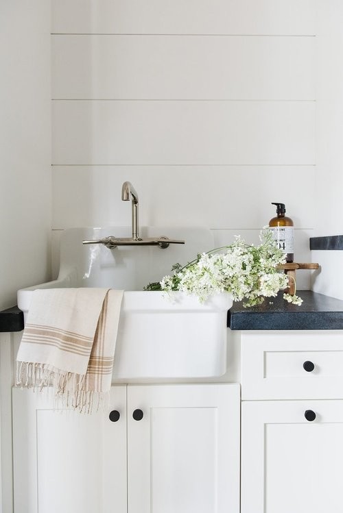 Foto på en liten flerfärgade parallell tvättstuga enbart för tvätt, med vita skåp, vita väggar, klinkergolv i keramik, en tvättmaskin och torktumlare bredvid varandra och svart golv
