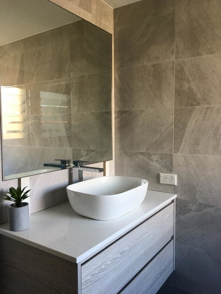Photo of a small modern single-wall separated utility room in Brisbane with a built-in sink, flat-panel cabinets, light wood cabinets, laminate countertops, grey walls, ceramic flooring, an integrated washer and dryer, black floors and grey worktops.