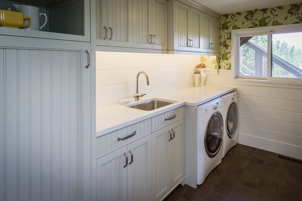 Imagen de cuarto de lavado lineal de estilo de casa de campo de tamaño medio con puertas de armario blancas, encimera de laminado, lavadora y secadora juntas, armarios con paneles empotrados, fregadero bajoencimera y paredes verdes