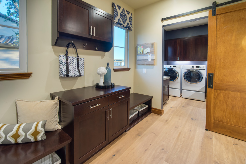 Foto på en grå tvättstuga enbart för tvätt, med en nedsänkt diskho, skåp i shakerstil, bruna skåp, granitbänkskiva, ljust trägolv, en tvättmaskin och torktumlare bredvid varandra och brunt golv