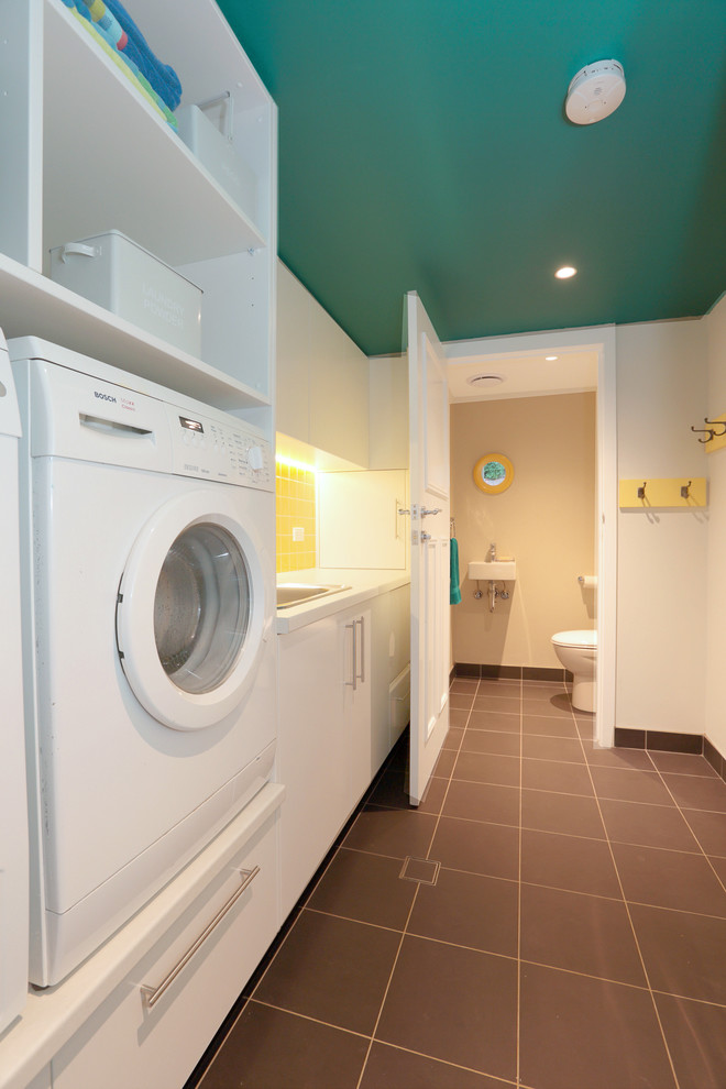 Zweizeilige, Mittelgroße Klassische Waschküche mit Einbauwaschbecken, flächenbündigen Schrankfronten, weißen Schränken, Laminat-Arbeitsplatte, Porzellan-Bodenfliesen und Waschmaschine und Trockner nebeneinander in Sydney