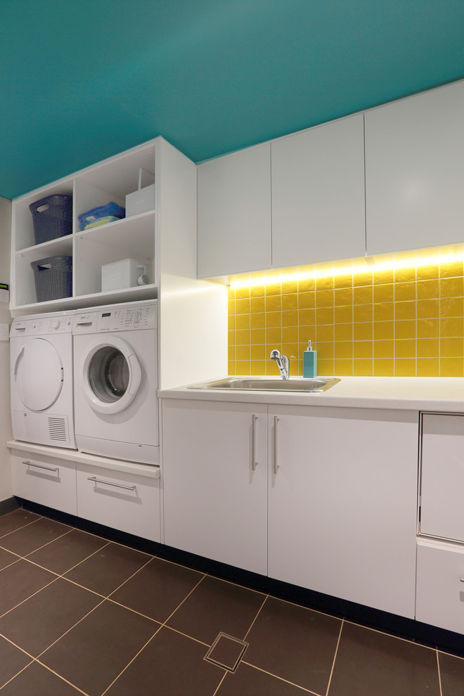 Idee per una sala lavanderia minimal di medie dimensioni con lavello da incasso, ante lisce, ante bianche, top in laminato, pavimento con piastrelle in ceramica e lavatrice e asciugatrice affiancate