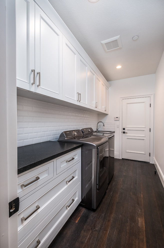 Medium sized traditional single-wall separated utility room in Orange County with a submerged sink, marble worktops, white walls, dark hardwood flooring, a side by side washer and dryer, brown floors, black worktops, recessed-panel cabinets and white cabinets.