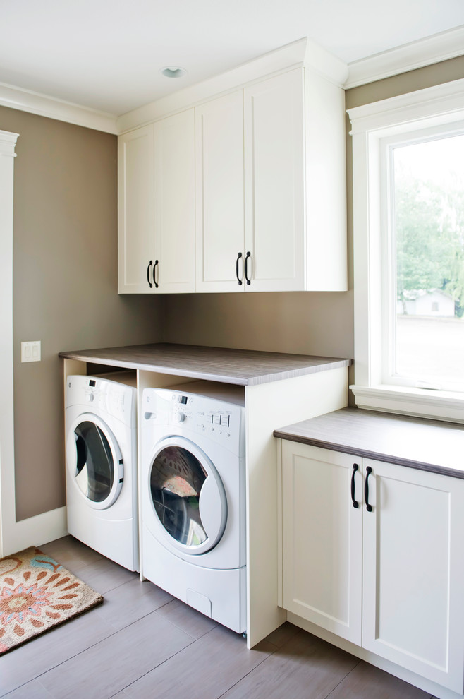 Example of a mid-sized transitional single-wall utility room design in Vancouver with shaker cabinets, white cabinets, laminate countertops, brown walls and a side-by-side washer/dryer