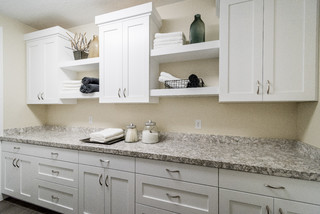 Classic cottage laundry room features a white and gray granite countertop  positioned over a sil…