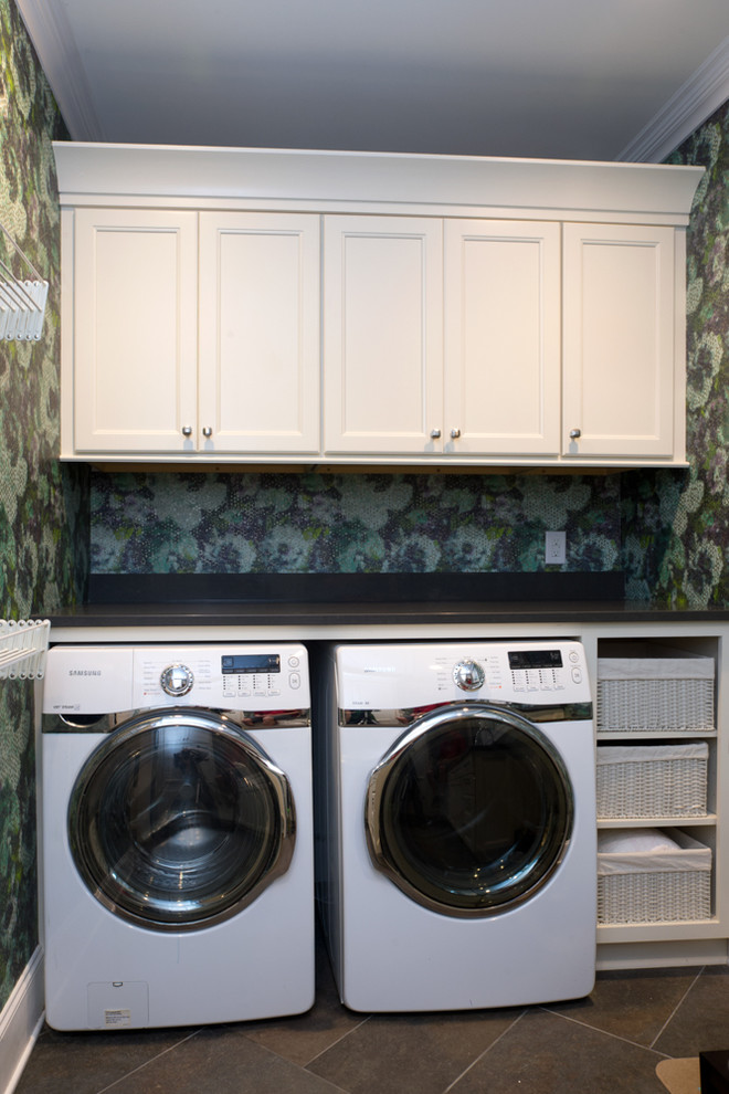 Inspiration för stora 60 tals u-formade tvättstugor enbart för tvätt, med luckor med infälld panel, vita skåp, bänkskiva i onyx, en tvättmaskin och torktumlare bredvid varandra, en undermonterad diskho, blå väggar och skiffergolv