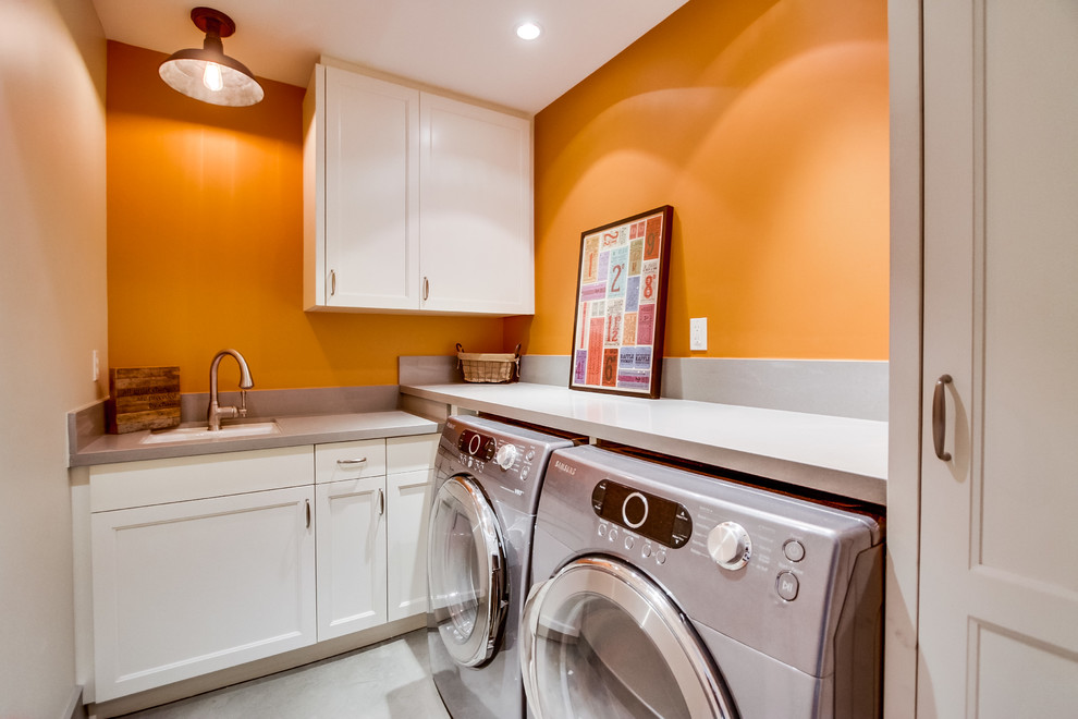 サンディエゴにあるトラディショナルスタイルのおしゃれなランドリールーム (アンダーカウンターシンク、オレンジの壁、左右配置の洗濯機・乾燥機、グレーのキッチンカウンター) の写真