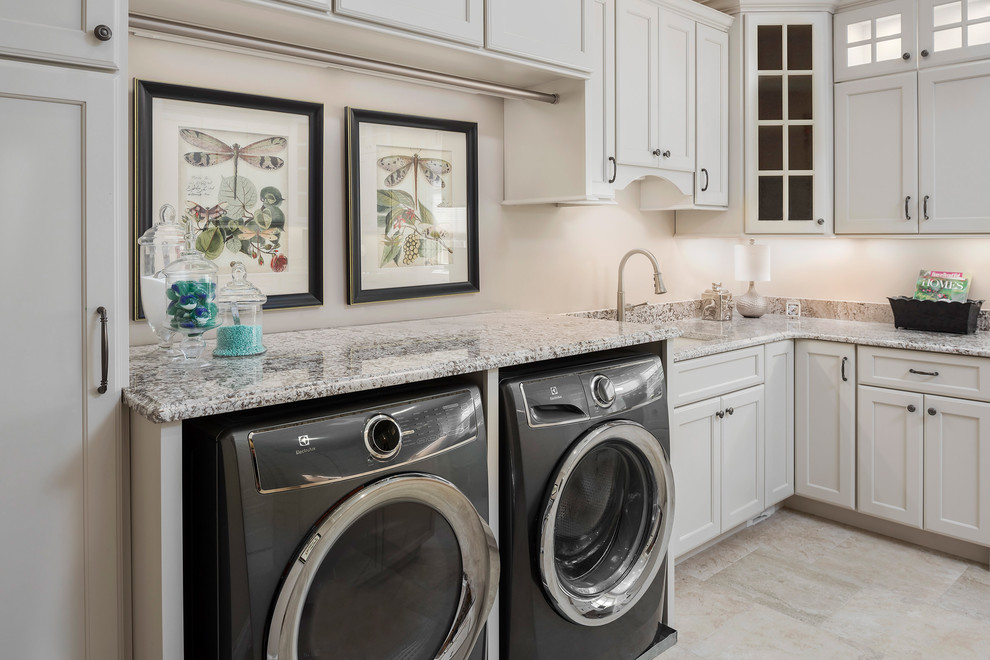 This is an example of a large traditional u-shaped utility room in St Louis with flat-panel cabinets, white cabinets, granite worktops, a side by side washer and dryer and beige floors.