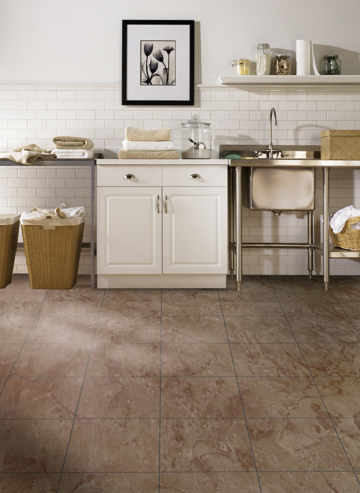 Exempel på en industriell vita vitt tvättstuga enbart för tvätt, med en allbänk, öppna hyllor, vita skåp, vita väggar, klinkergolv i porslin, en tvättmaskin och torktumlare bredvid varandra och brunt golv