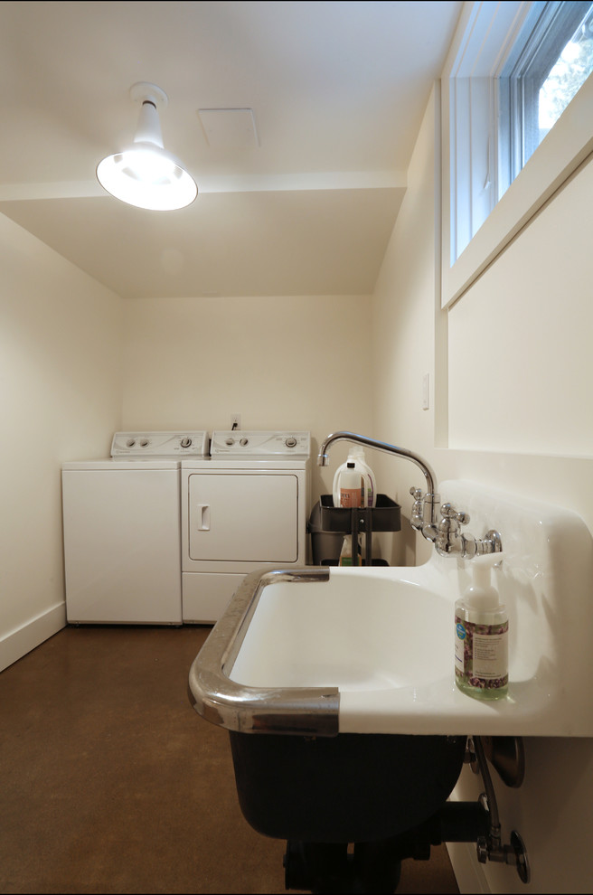 Ispirazione per una sala lavanderia tradizionale di medie dimensioni con lavatoio, pareti bianche, pavimento in cemento e lavatrice e asciugatrice affiancate