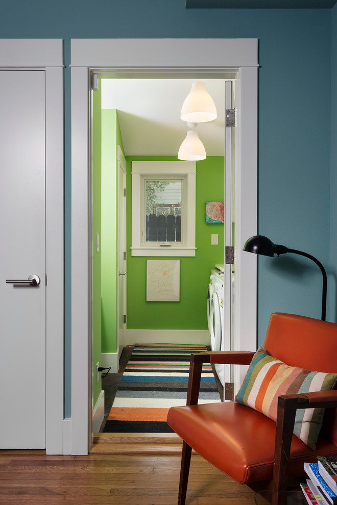 Immagine di una piccola sala lavanderia design con lavello da incasso, ante bianche, top in laminato, pareti verdi, pavimento in cemento e lavatrice e asciugatrice affiancate