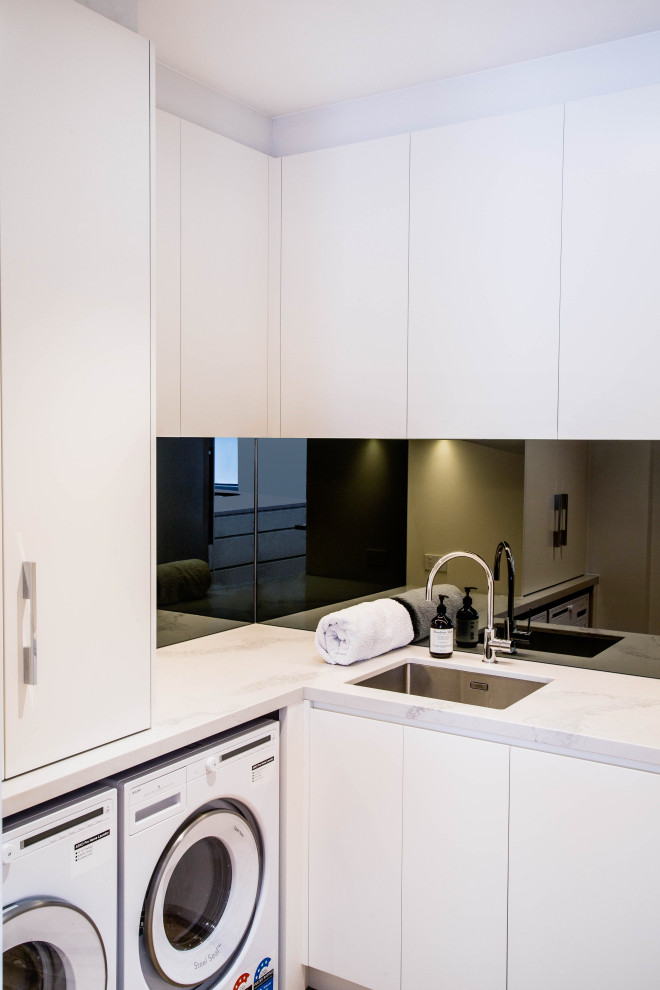 This is an example of a small traditional l-shaped separated utility room in Melbourne with a submerged sink, flat-panel cabinets, white cabinets, engineered stone countertops, white walls, light hardwood flooring, a side by side washer and dryer, yellow floors and multicoloured worktops.