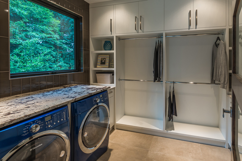 Moderne Waschküche mit flächenbündigen Schrankfronten, weißen Schränken, Granit-Arbeitsplatte, Porzellan-Bodenfliesen und Waschmaschine und Trockner nebeneinander in Vancouver