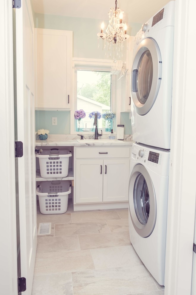 Klassisk inredning av en vita vitt tvättstuga enbart för tvätt, med en allbänk, luckor med infälld panel, vita skåp, laminatbänkskiva, blå väggar, en tvättpelare, vitt golv och klinkergolv i porslin