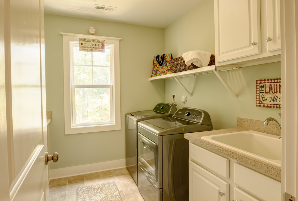 Esempio di una sala lavanderia minimal di medie dimensioni con lavello da incasso, ante con bugna sagomata, ante bianche, pareti verdi, pavimento con piastrelle in ceramica, lavatrice e asciugatrice affiancate e pavimento beige