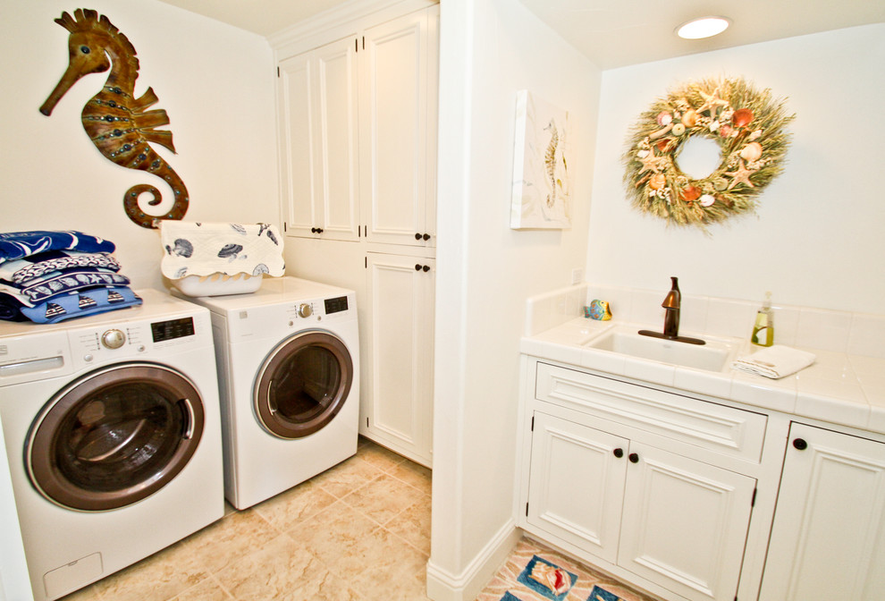 Immagine di una lavanderia multiuso di medie dimensioni con lavello da incasso, top piastrellato, pareti bianche e lavatrice e asciugatrice affiancate