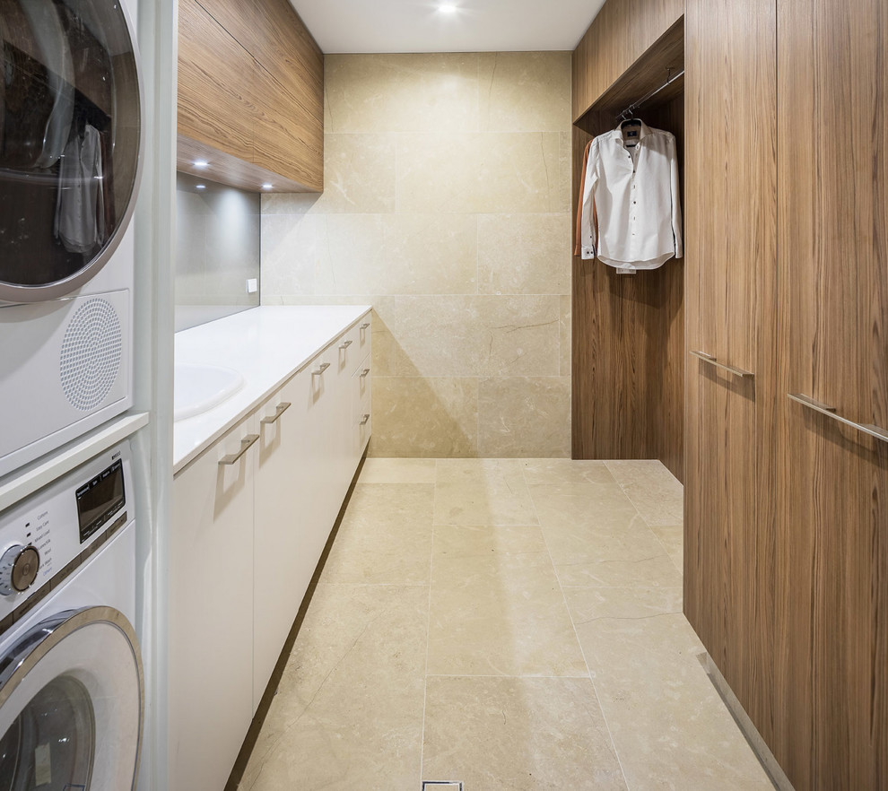 Large contemporary galley separated utility room in Perth with a single-bowl sink, flat-panel cabinets, engineered stone countertops, limestone flooring, a stacked washer and dryer and dark wood cabinets.