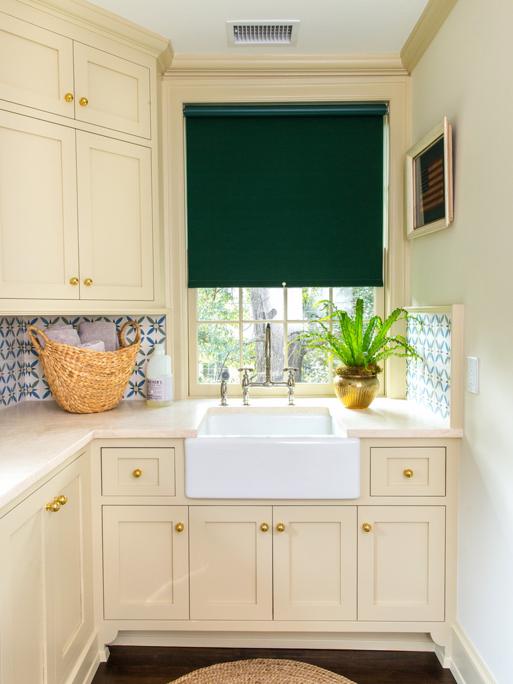 Inspiration för små klassiska l-formade gult tvättstugor enbart för tvätt, med en rustik diskho, skåp i shakerstil, mörkt trägolv, bänkskiva i kvarts, beige skåp och vita väggar