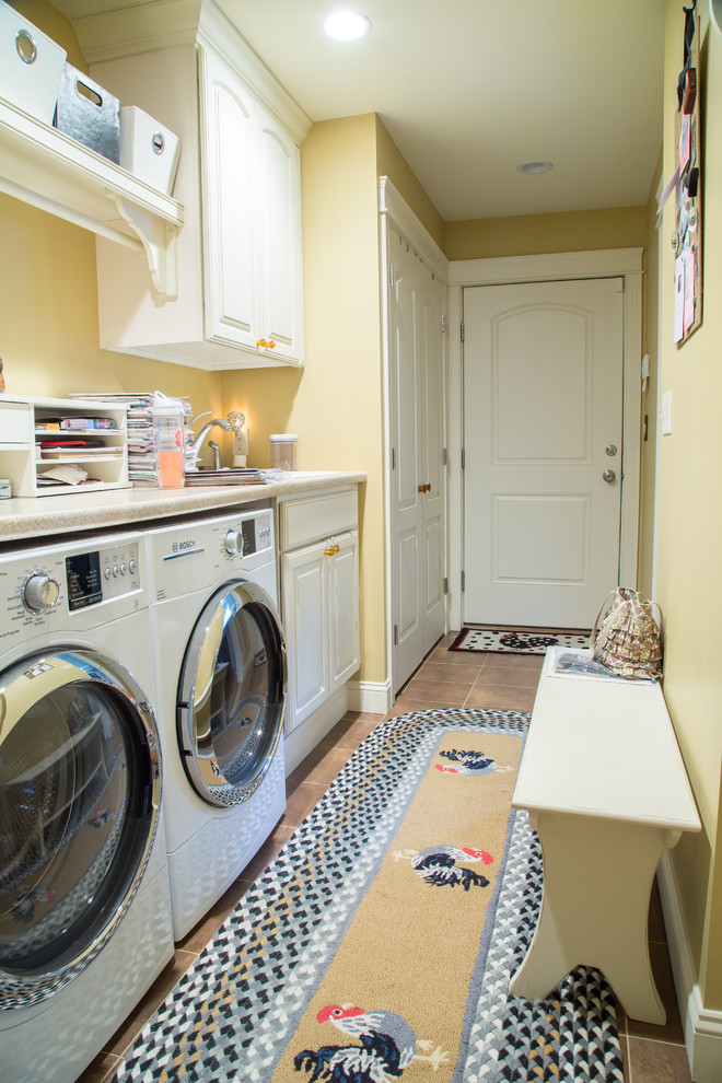 Exempel på en tvättstuga, med gula väggar och en tvättmaskin och torktumlare bredvid varandra