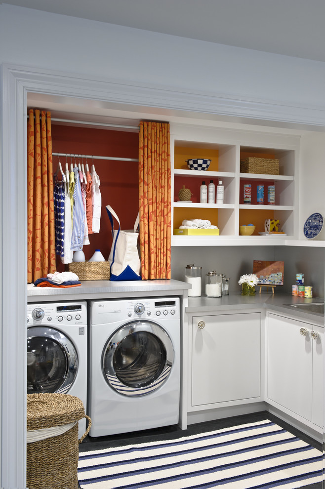 Immagine di una sala lavanderia tradizionale con lavatrice e asciugatrice affiancate, ante bianche e top grigio