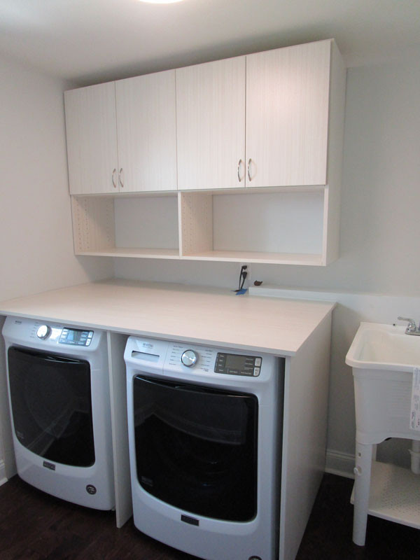 Einzeilige, Kleine Moderne Waschküche mit Ausgussbecken, flächenbündigen Schrankfronten, beiger Wandfarbe und Waschmaschine und Trockner nebeneinander in Sonstige