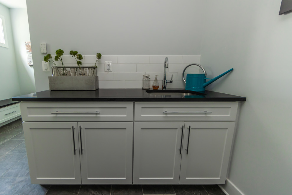 Photo of a large traditional galley utility room in Baltimore with shaker cabinets, white cabinets, composite countertops, grey walls, porcelain flooring, a side by side washer and dryer, grey floors, black worktops and a submerged sink.