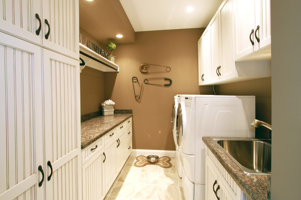 Foto på ett mellanstort vintage parallellt grovkök, med vita skåp, granitbänkskiva, bruna väggar, en tvättmaskin och torktumlare bredvid varandra, luckor med infälld panel och en nedsänkt diskho