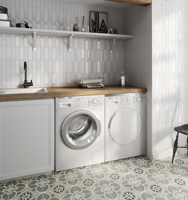 Bild på en mellanstor funkis linjär tvättstuga enbart för tvätt, med en nedsänkt diskho, träbänkskiva, vita väggar, klinkergolv i porslin, en tvättmaskin och torktumlare bredvid varandra och flerfärgat golv