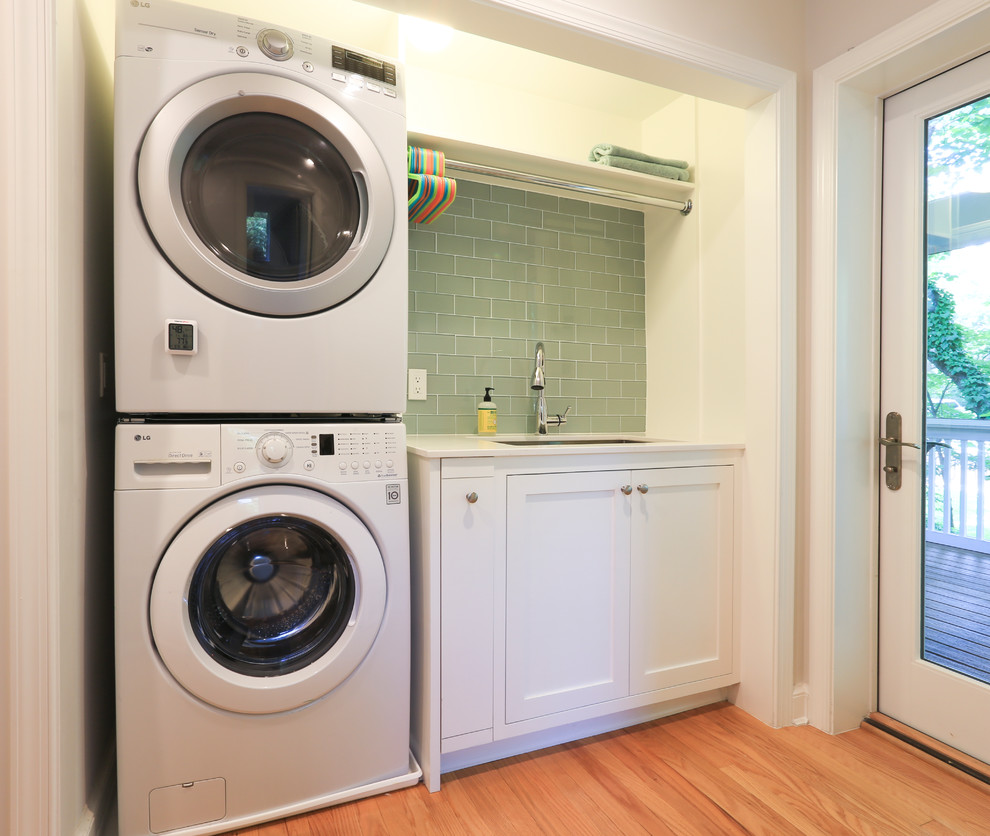 Idéer för små vintage linjära vitt tvättstugor enbart för tvätt, med en undermonterad diskho, luckor med infälld panel, vita skåp, bänkskiva i kvarts, beige väggar, ljust trägolv, en tvättpelare och brunt golv